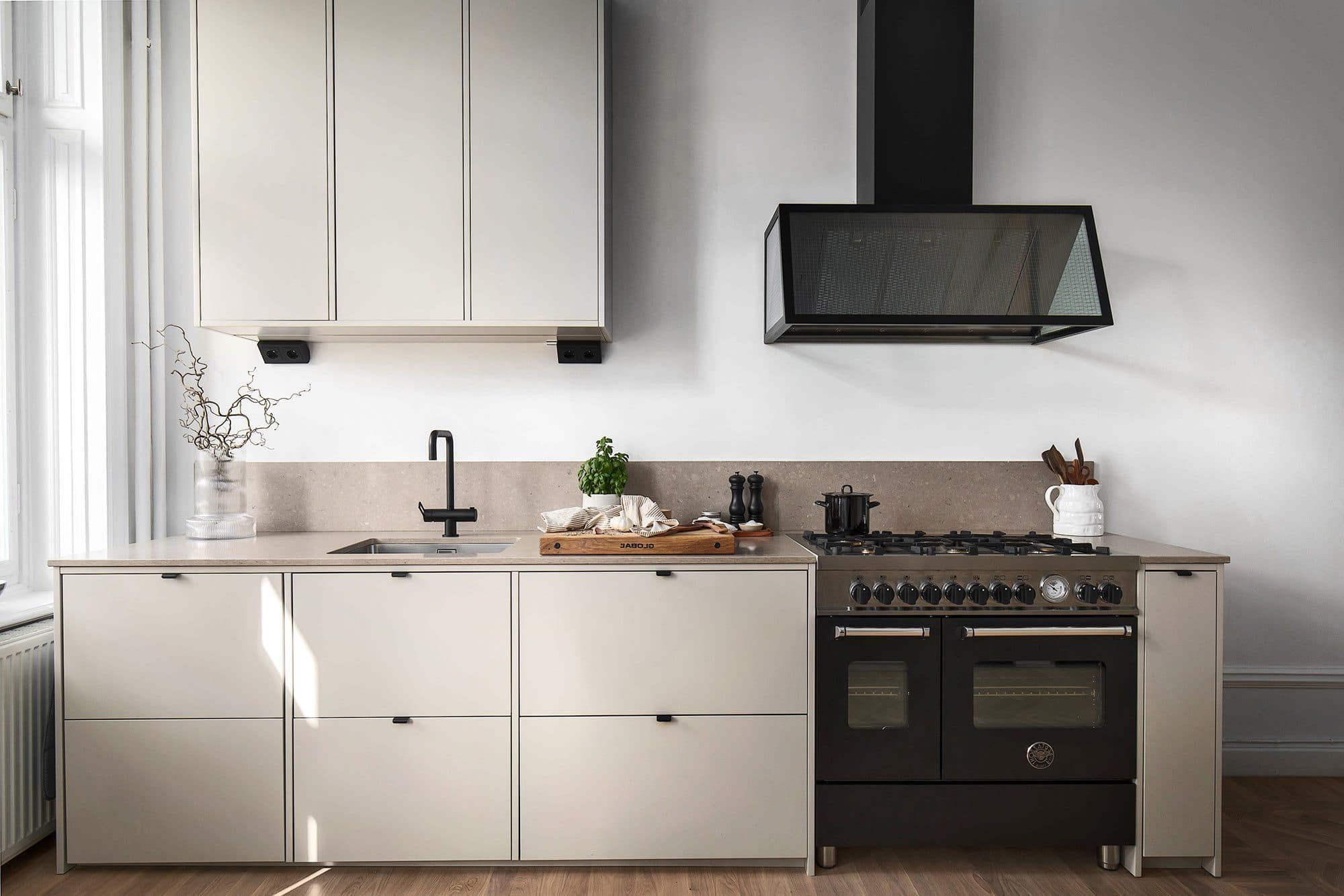 Beige köksluckor med svarta vitvaror