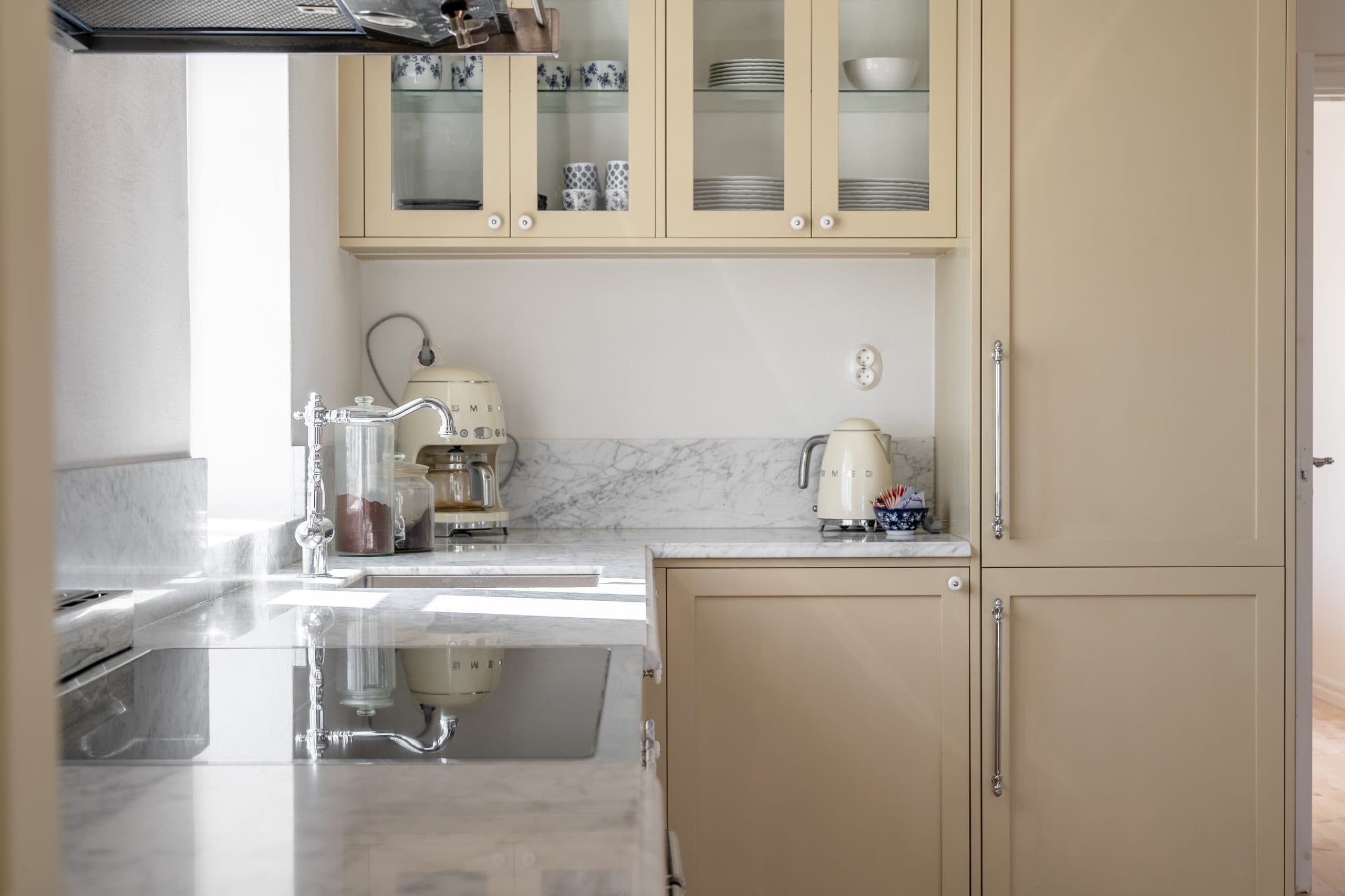 Lantligt gult kök med vitrinskåp