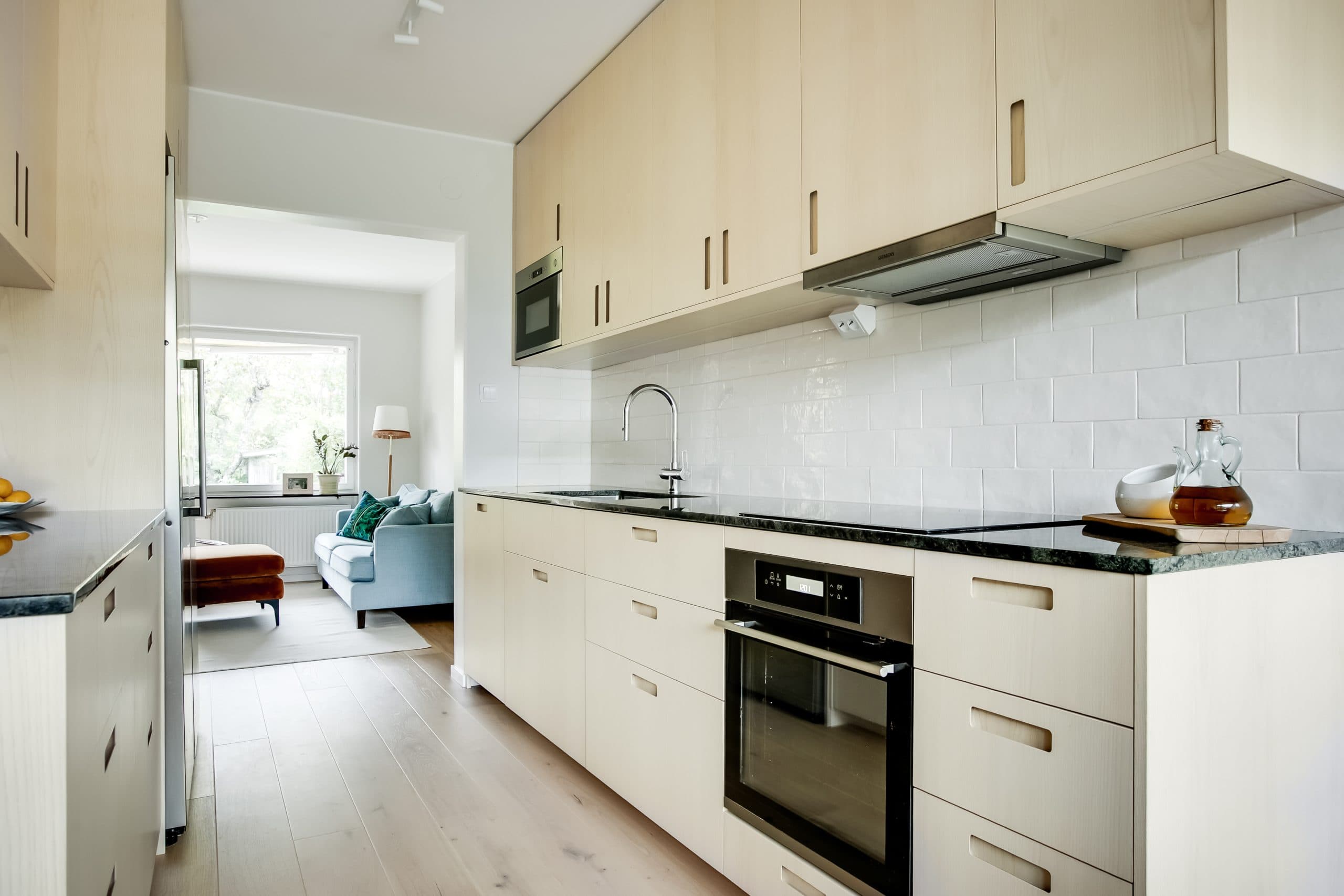 Parallellkök med ljusa köksluckor i vitlaserad ask